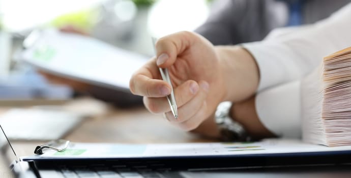 Group of people working with financial reports clipped to pad at workplace closeup