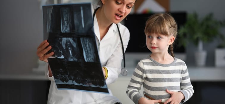 Child doctor specialist look x-ray image in hospital office portrait. Bone tratment concept