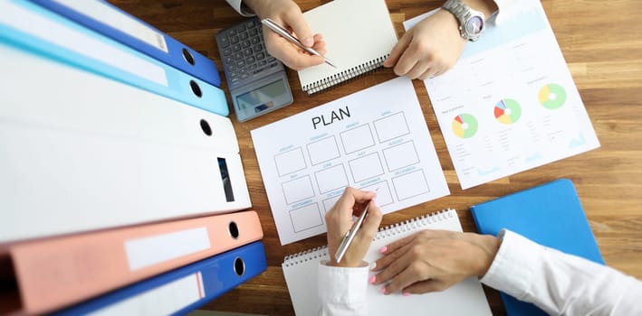 Businessman and businesswoman make work plan 2020 on office table with folder paper background. Business paperwork concept