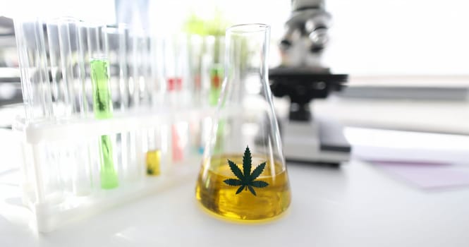 Test tube with natural extract cbd oil in chemisrtry lab research background closeup. Medical marijuana concept
