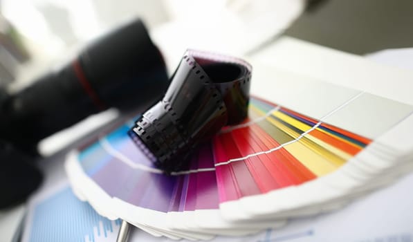 Close-up of catalog with multicolored color samples and camera. Designers tools and equipment for creating new project. Creative office concept. Blurred background