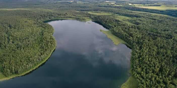 Topview on natural panorama beautiful lake with wild nature outdoor. Green forest, shore and water with cloudy reflection on it. Picturesque landscape scene