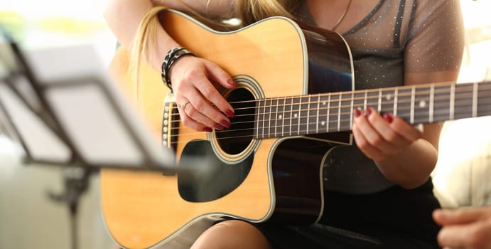 Female hands holding and playing western acoustic guitar closeup process