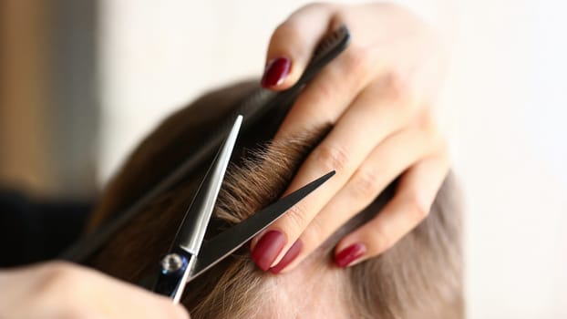 Female hand hold hair scissors aganist hairdresser salon background