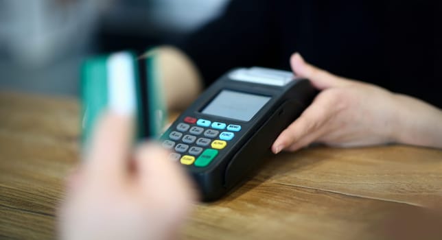 Customer paying with credit card via payment terminal at cash desk background concept