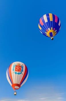 Two multicolored balloons with a striped pattern soar in the clear blue sky, Belarus, Minsk