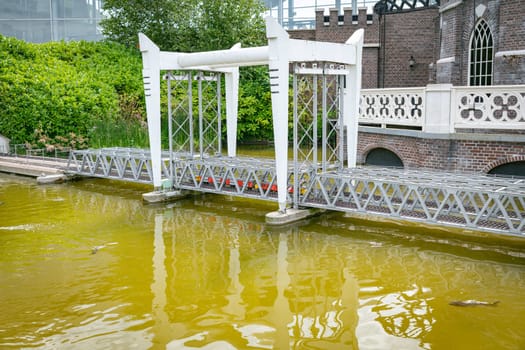 the haque,holland,09-07-2024:Toy dutch post train over the bridge over the river in a miniature city in Madurodam park, Netherlands.