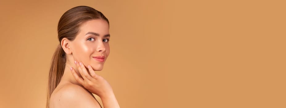 Beauty and fashion. Sexy young lady with silky hair and soft skin touching her face on beige background, copy space