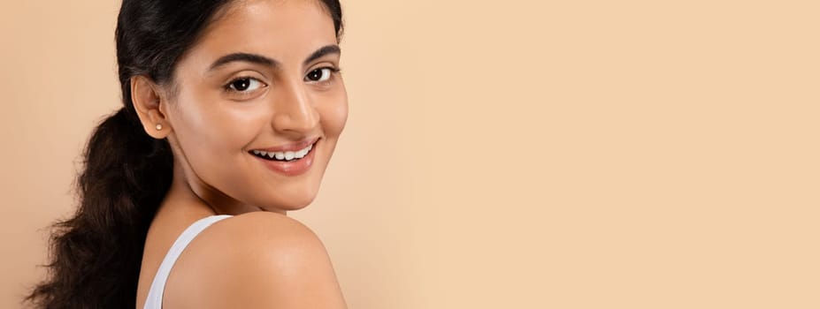 Closeup Shot Of Attractive Young Indian Woman With Beautiful Skin, Portrait Of Smiling Eastern Lady With Natural Beauty Looking At Camera, Posing Isolated Over Beige Studio Background, Free Space