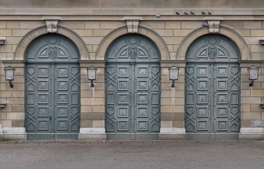 Munich, Germany - Dec 21, 2023 - Facade of arched iron doorway with lamps on stone wall of The Munich Residence Building. Architectural detail of Renaissance baroque style, Space for text, Selective focus.