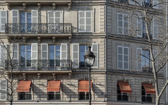 France, Paris - Jan 05, 2024 - Facade of elegant apartment buildings in the cities of Paris are patterned with french windows and wrought iron black railings. Exterior architecture of Traditional French house with typical balconies and windows in Paris, Copy space, Selective focus.