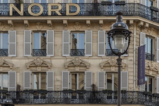 France, Paris - Jan 05, 2024 - Exterior architecture of Traditional French house with typical balconies and windows in Paris. Facade of elegant apartment buildings in the cities of Paris are patterned with french windows and wrought iron black railings, Space for text, Selective focus.