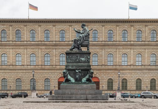 Munich, Germany - Dec 21, 2023 - Side view of Monument Bronze Statue of King Maximilian I Joseph of Bavaria with The Munich Residence Museum Building at the Max Joseph Square in central Munich. Space for text, Selective focus.