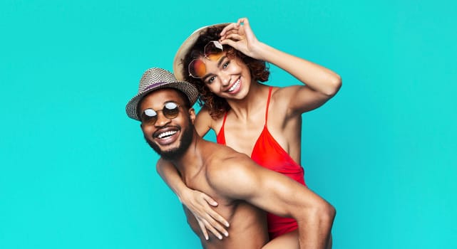 African American couple, a man and a woman, posing against a bright blue background. They are enjoying themselves and celebrating summer.