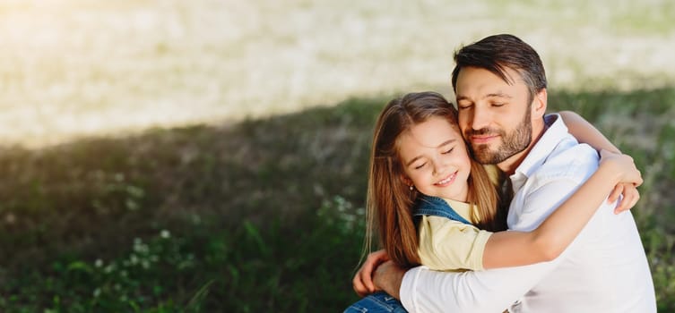 Daughter's love. Little girl hugging her father, having picnic in park