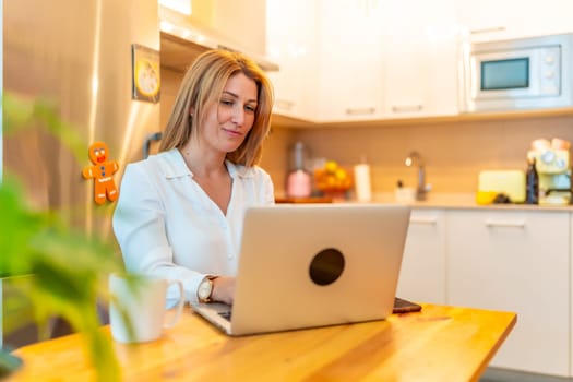 Beauty caucasian blonde woman sitting on the living room using laptop working from home
