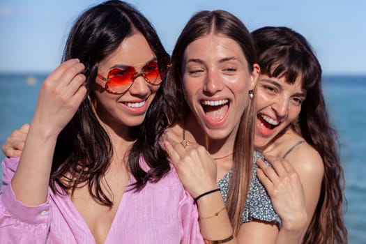Group of smiling multiethnic women wearing hats and sunglasses enjoying vacation. Beautiful and cheerful Gen Z girls pose looking at the camera