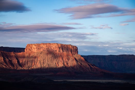 Breathtaking sunrise view of a striking mesa in Moab, Utah. The warm, golden glow illuminates the rugged landscape, highlighting the natural beauty and dramatic geology of the region - USA
