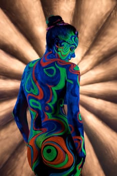 Slim girl posing in smoky studio her face and figure covered by bright fantastic ultraviolet color pattern bodyart.