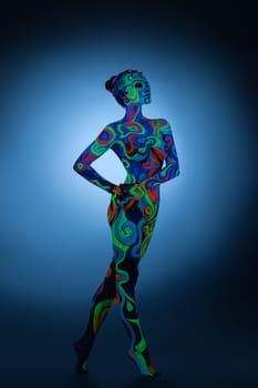 Slim girl posing in studio her face and figure covered by bright fantastic ultraviolet color pattern bodyart.