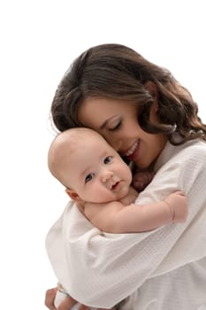 Young pretty mother keeping lovely baby boy in her arms smiling affectionately at him studio shot