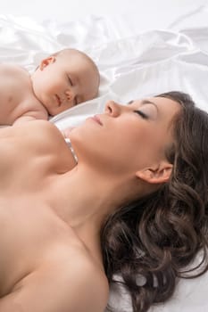 Young pretty mother and her lovely baby boy sleeping studio shot