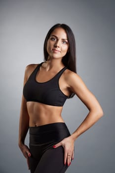 Pretty young fitness trainer in black top and leggings studio portrait