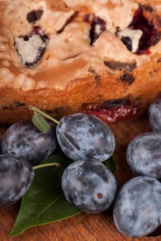 dessert cakes and fresh plums on old wooden table