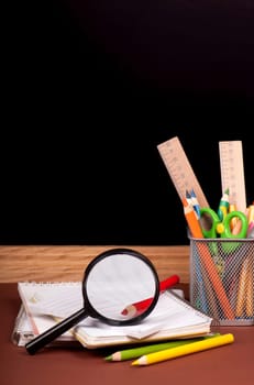 board, books, pencils, opened empty notebook against a dark background