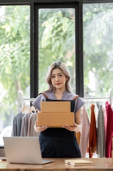 Online business concept, Asian business women holds parcel boxes of product for delivery to client.