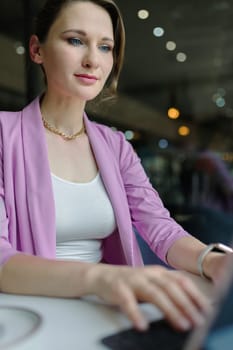 Young woman entrepreneur working on a laptop in a cafe, freelance work concept, vertical.