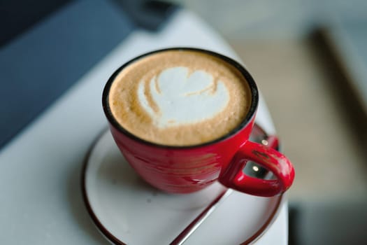 Red cup of coffee, cappuccino with heart shape, drink to good morning.