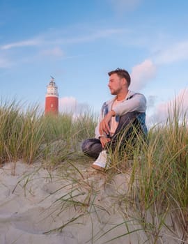 Texel lighthouse during sunset Netherlands Dutch Island Texel Holland, young men watching sunset on the sand dunes by the lighthouse of the Dutch Island Texel