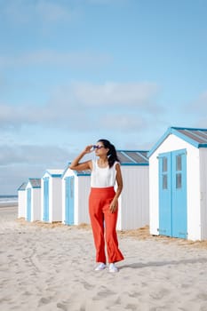 Asian women visiting the beach of Texel with on the background the white blue house on the beach of Texel Netherlands, a beach hut on the Dutch Island of Texel