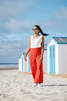 Asian women visiting the beach of Texel with on the background the white blue house on the beach of Texel Netherlands, a beach hut on the Dutch Island of Texel