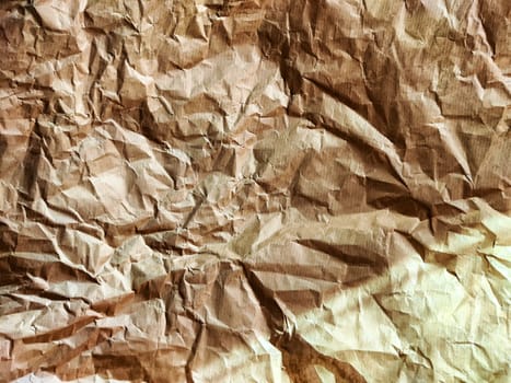 Heavily crumpled textured kraft paper in sunlight and with shadow. Abstract background, texture, frame, place for text and copy space