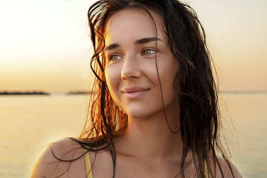 Smiling young woman relaxing on the beach during sunrise.