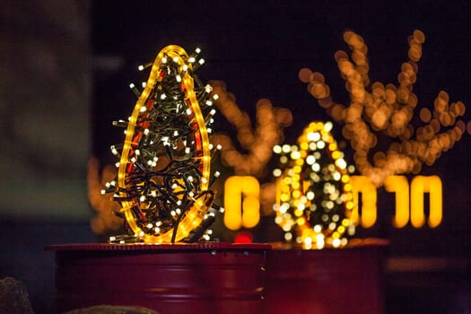 Occasional glowing Christmas and New Year decorations hang in the square, shot at night
