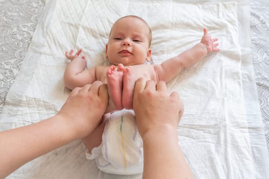 Mother uses massage technique on baby's leg. Concept of traditional colic and constipation relief