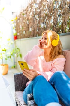 Vertical photo of a caucasian adult woman listening to music and using mobile phone in the courtyard