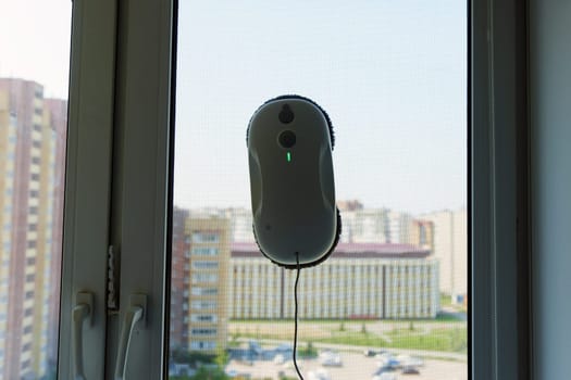 Cleaning robot washing the outside glass of window with beautiful view of sky.
