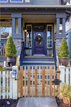 Entrance of luxury residential house with unpainted wooden gate in front.
