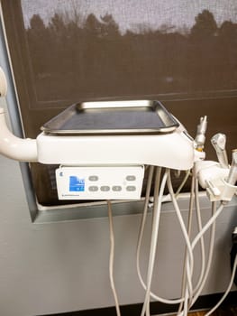 Denver, Colorado, USA-January 11, 2024-Close-up view of advanced dental office equipment, possibly an ultrasonic cleaner or other sterilization unit, set against a stainless-steel backdrop. It features a prominent digital interface and is connected by various tubes and cords, suggesting its role in patient care procedures.