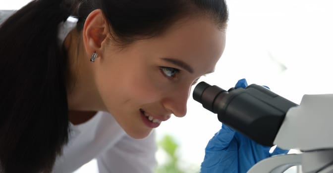 Portrait of pharmacy scientist working with professional microscope in technology lab. Laboratory with research equipment for virus study or vaccine development