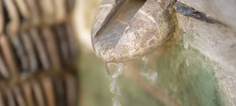 Close-up of water source in mountain, spring water or well-water with stone channel. Unpolluted natural well-water concept