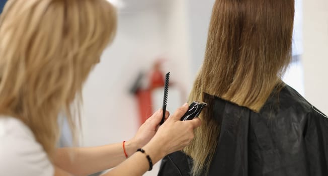 Close-up of process of hair cutting at beauty salon, using hair clipper. Beauty day, making haircut