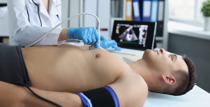 Close-up of doctor doing ultrasound of rib cage, cardiologist examining a patients heart. Person on planned checkup in hospital. Ultrasound and healthcare concept