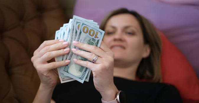 Close-up of happy smiling woman counting money at home. Cheerful female holding cash in hands. Business, finances and increase income concept
