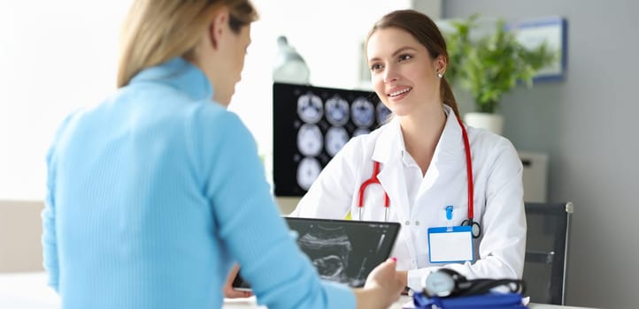 Portrait of pregnant woman at doctor appointment, ultrasound picture. Future mom looking at ultrasound pic of child. Happy pregnancy concept