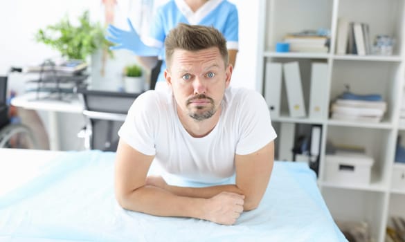 Portrait of guy at doctor appointment, nurse in manipulation room. Adult man afraid of injections. Medicine, treatment and healthcare concept